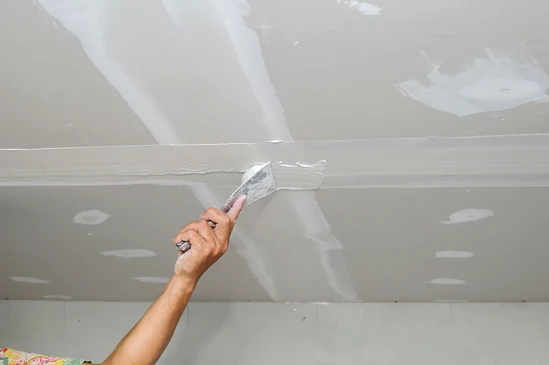 Les ouvriers du bâtiment placent des panneaux de plâtre ou de plâtre sur le mur avec la truelle