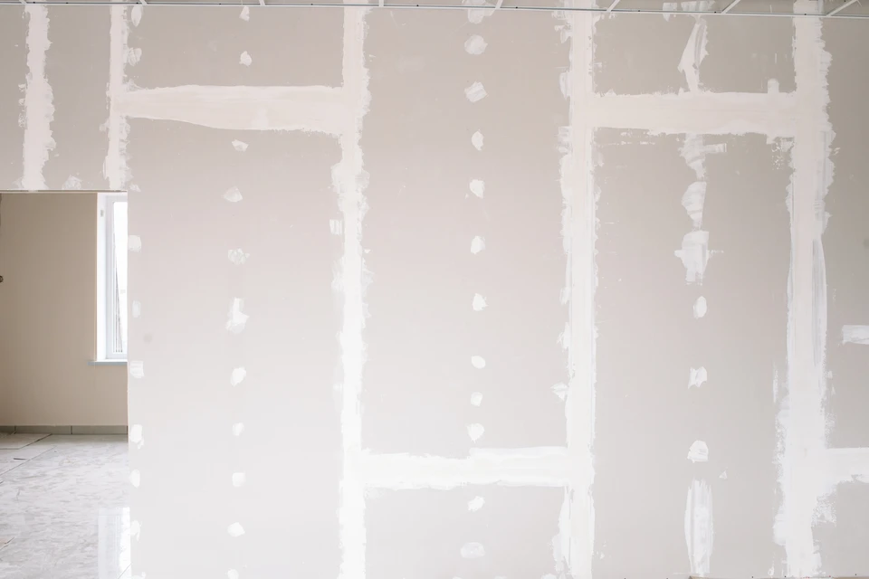 Ouvrier en salopette appliquant de l'enduit au plafond dans une pièce en rénovation